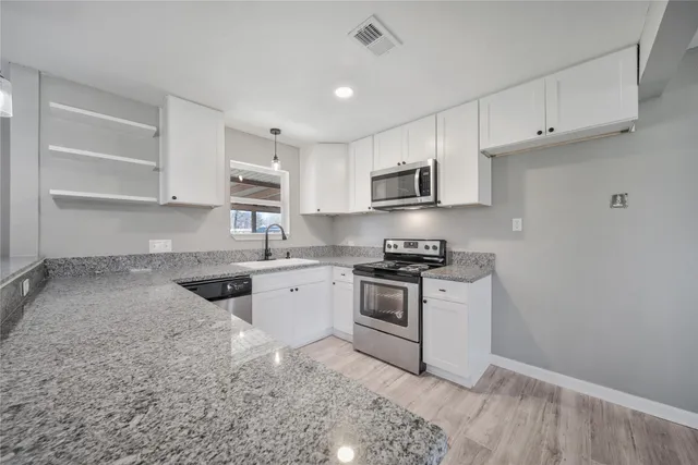 a kitchen with granite countertop a stove sink and cabinets