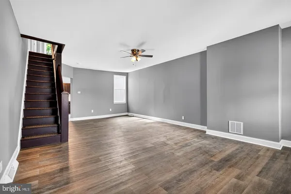 a view of an empty room with window and wooden floor