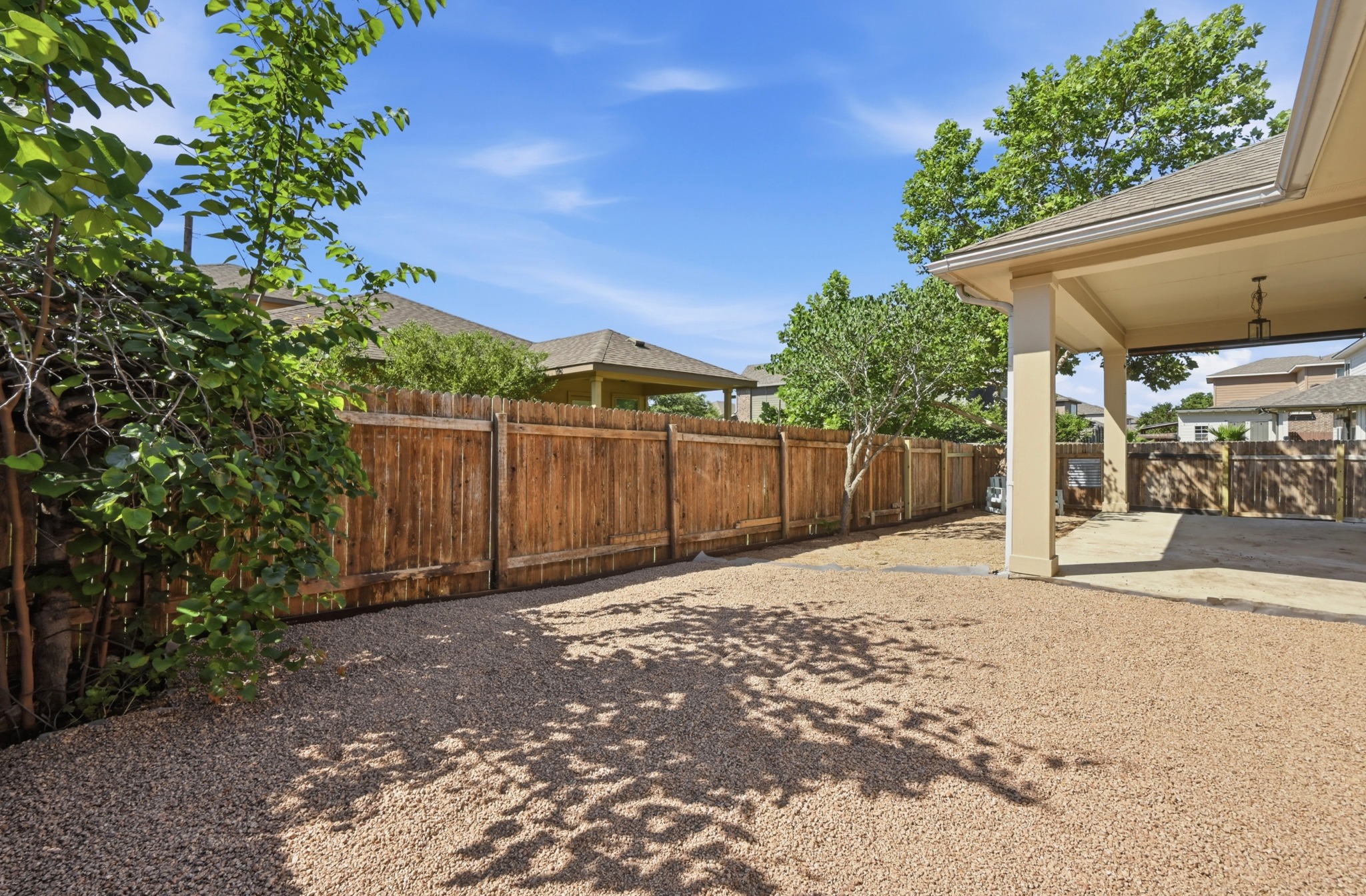 351 Wincliff Drive Buda, TX 78610 - Photo 33 of 40 Secure backyard featuring natural wood fencing, a covered patio, and ample gravel landscaping.