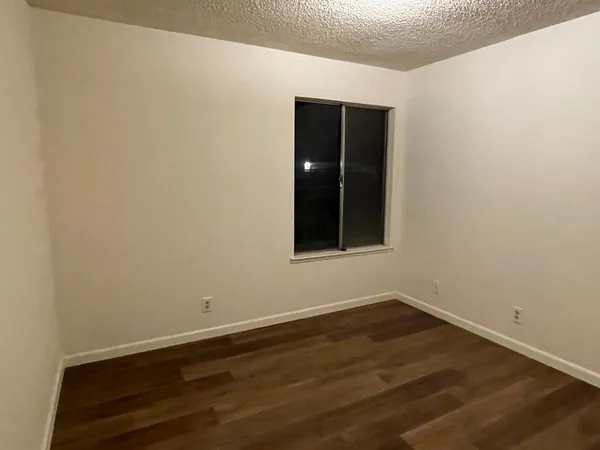 a view of an empty room with wooden floor and closet