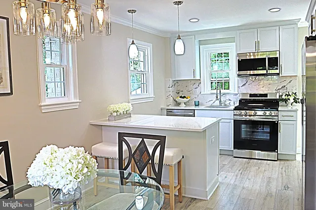 a kitchen with stainless steel appliances kitchen island granite countertop a stove a sink dishwasher a dining table and chairs with wooden floor