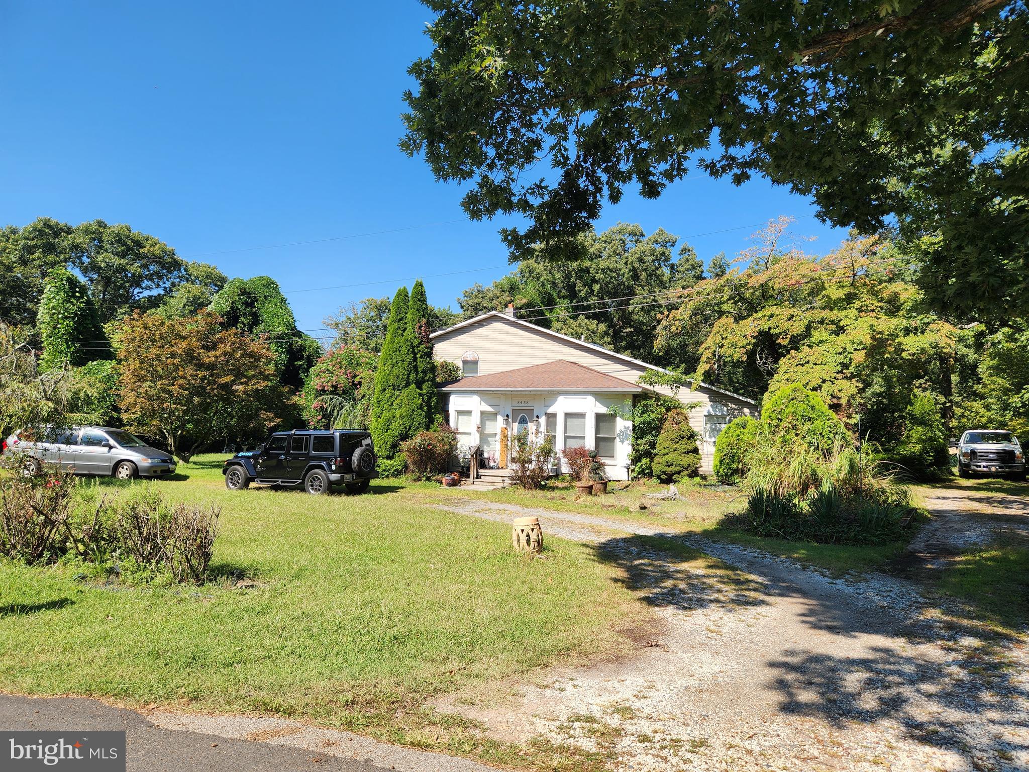 8458 Bussenius Road Pasadena, MD 21122 - Photo 2 of 4 a view of a white house with a yard plants and large tree