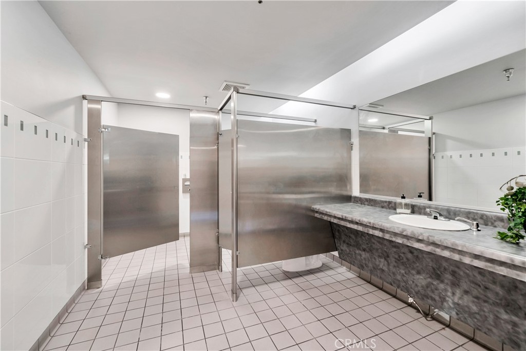 24691 Del Prado Avenue, Unit 100 Dana Point, CA 92629 - Photo 18 of 31 a bathroom with a double vanity sink mirror and shower