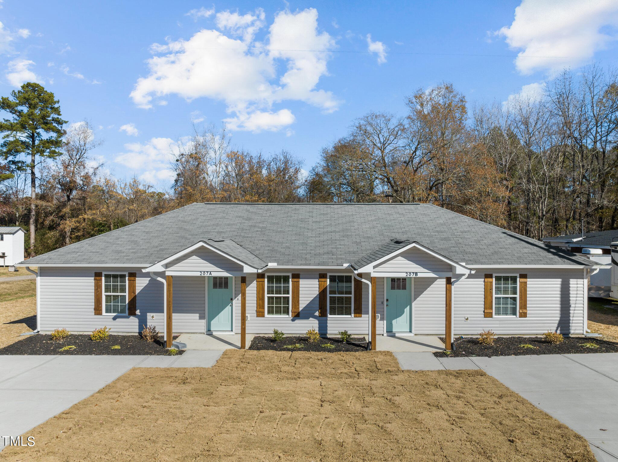207 South Nash Street, Unit AB Bunn, NC 27508 - Photo 1 of 25 a front view of a house with a garden and trees