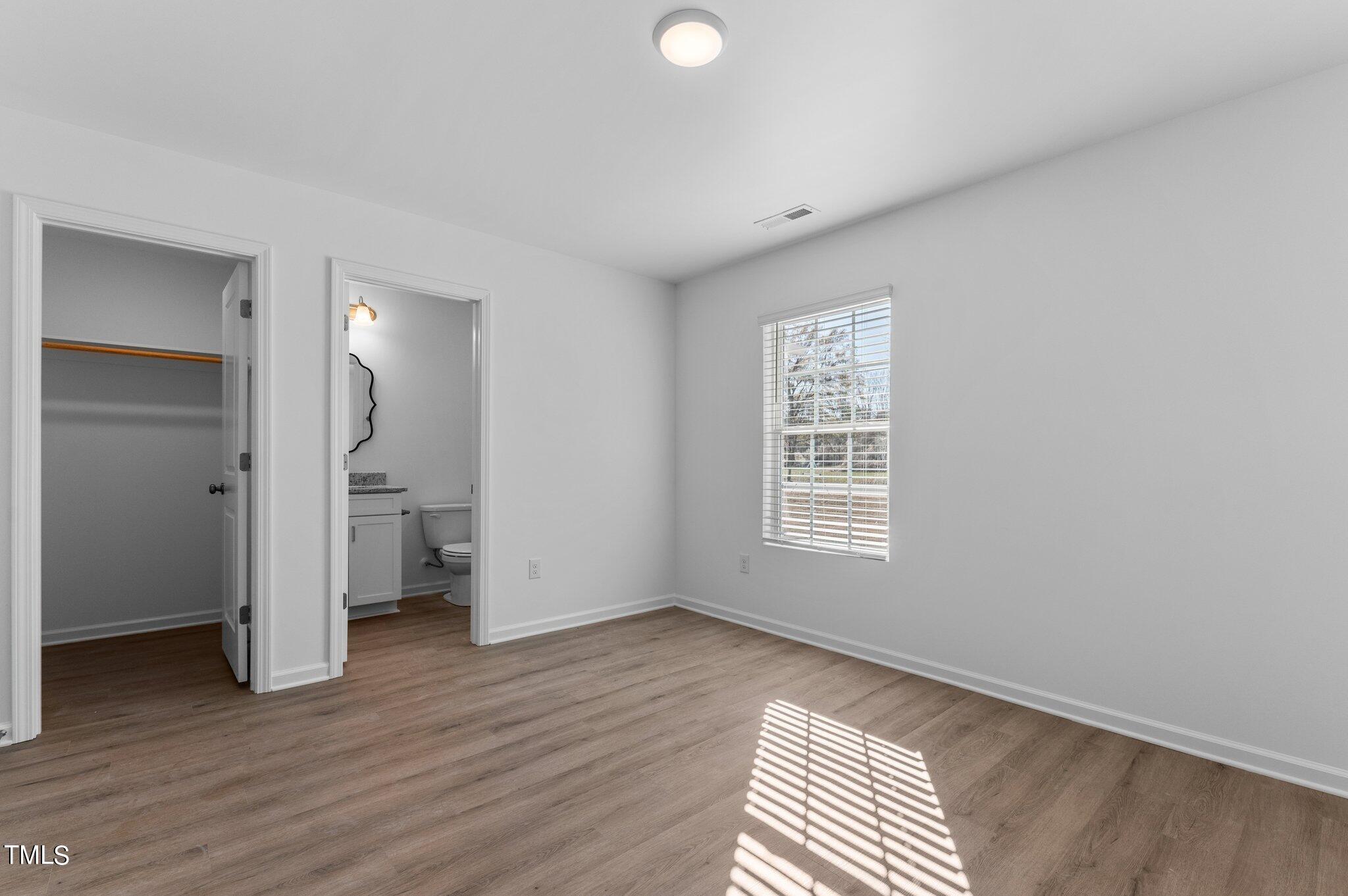 207 South Nash Street, Unit AB Bunn, NC 27508 - Photo 11 of 25 a view of an empty room with a window and wooden floor