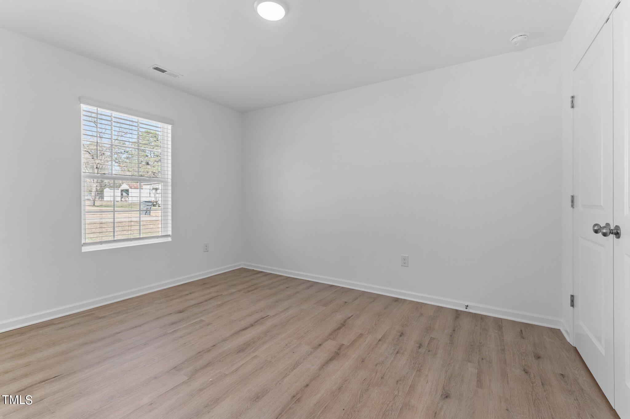 207 South Nash Street, Unit AB Bunn, NC 27508 - Photo 14 of 25 an empty room with wooden floor and windows