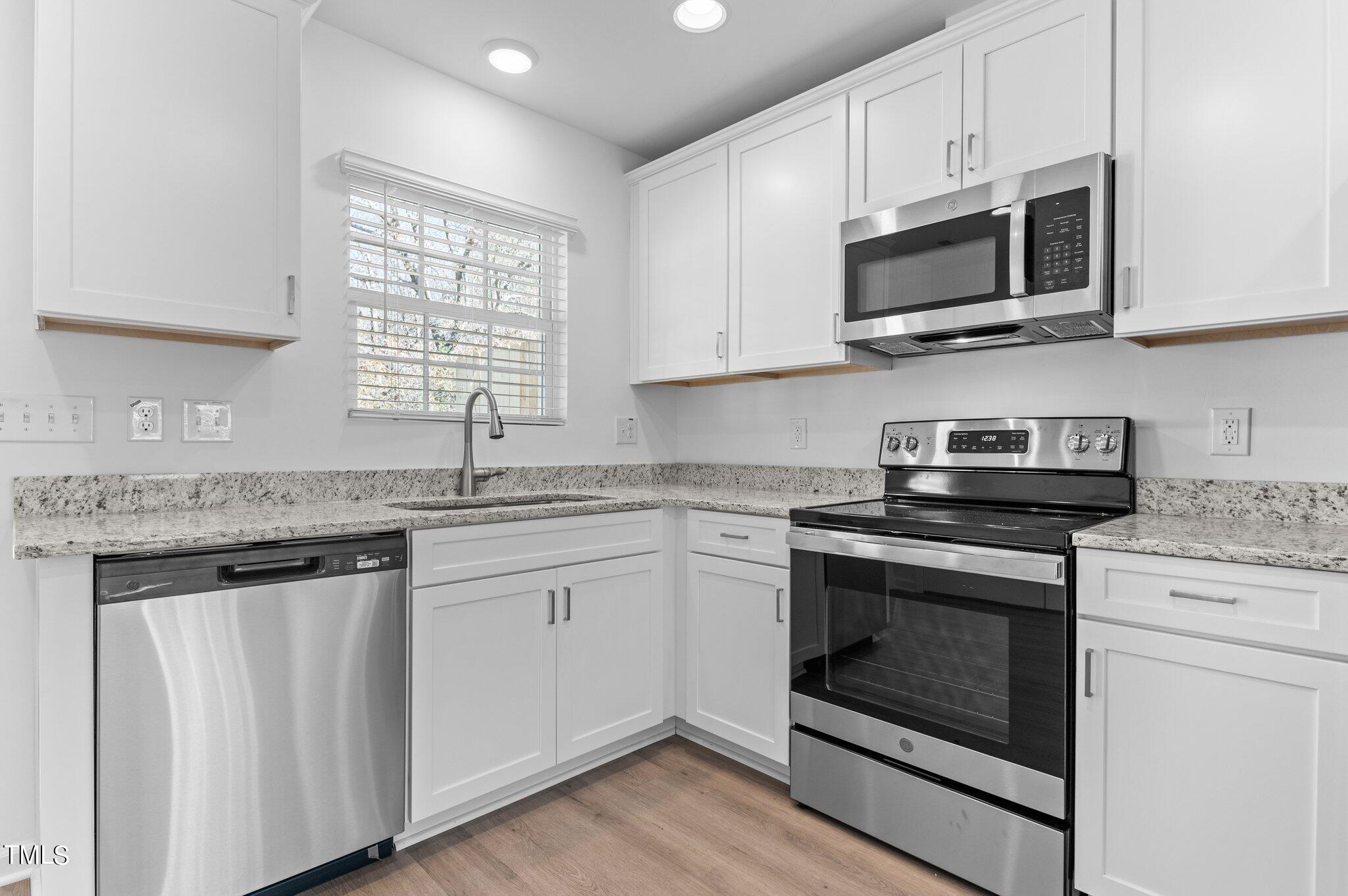 207 South Nash Street, Unit AB Bunn, NC 27508 - Photo 4 of 25 a kitchen with granite countertop white cabinets stainless steel appliances and a sink