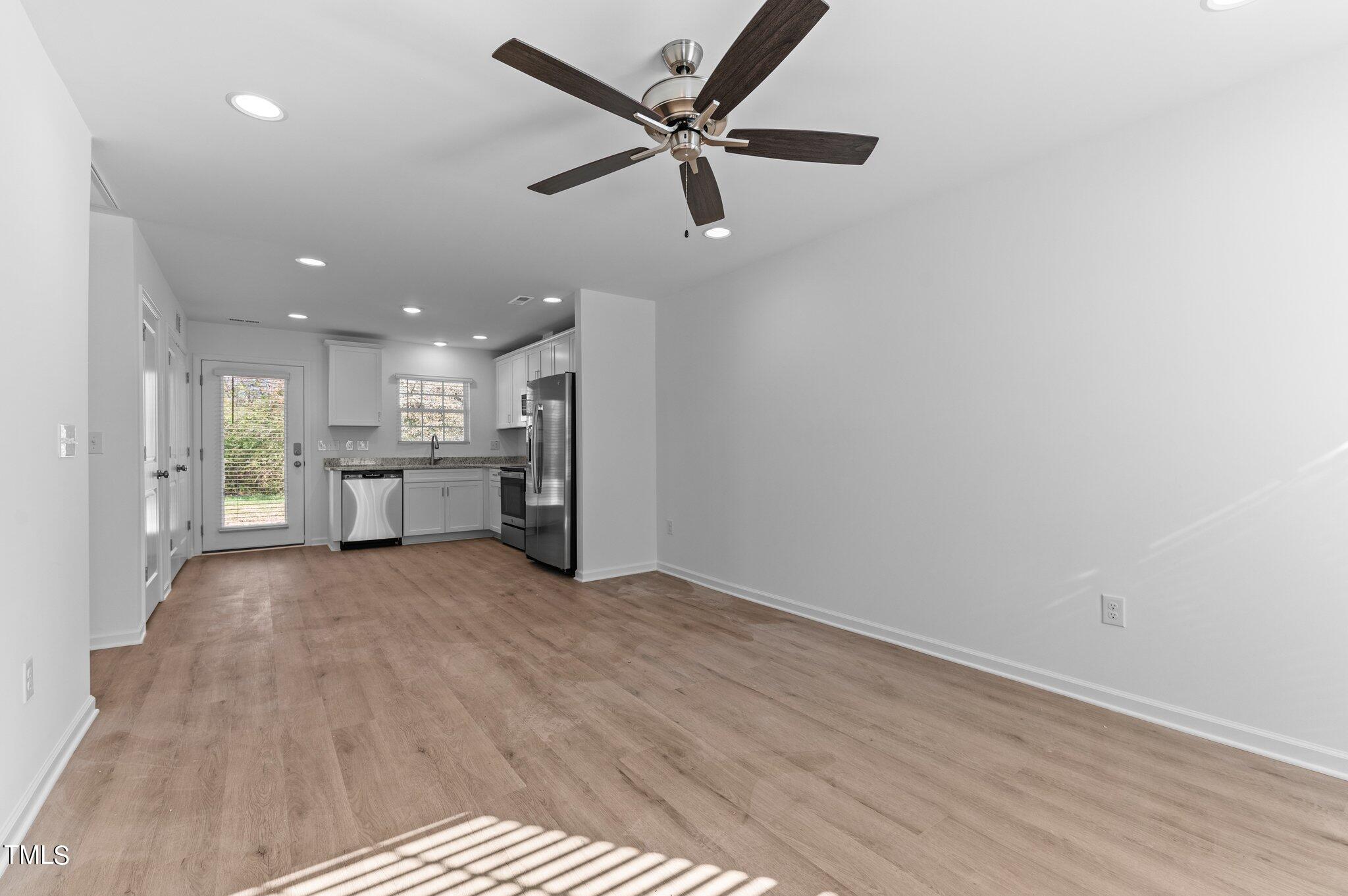207 South Nash Street, Unit AB Bunn, NC 27508 - Photo 6 of 25 a view of a livingroom with a kitchen stove wooden floor and a ceiling fan