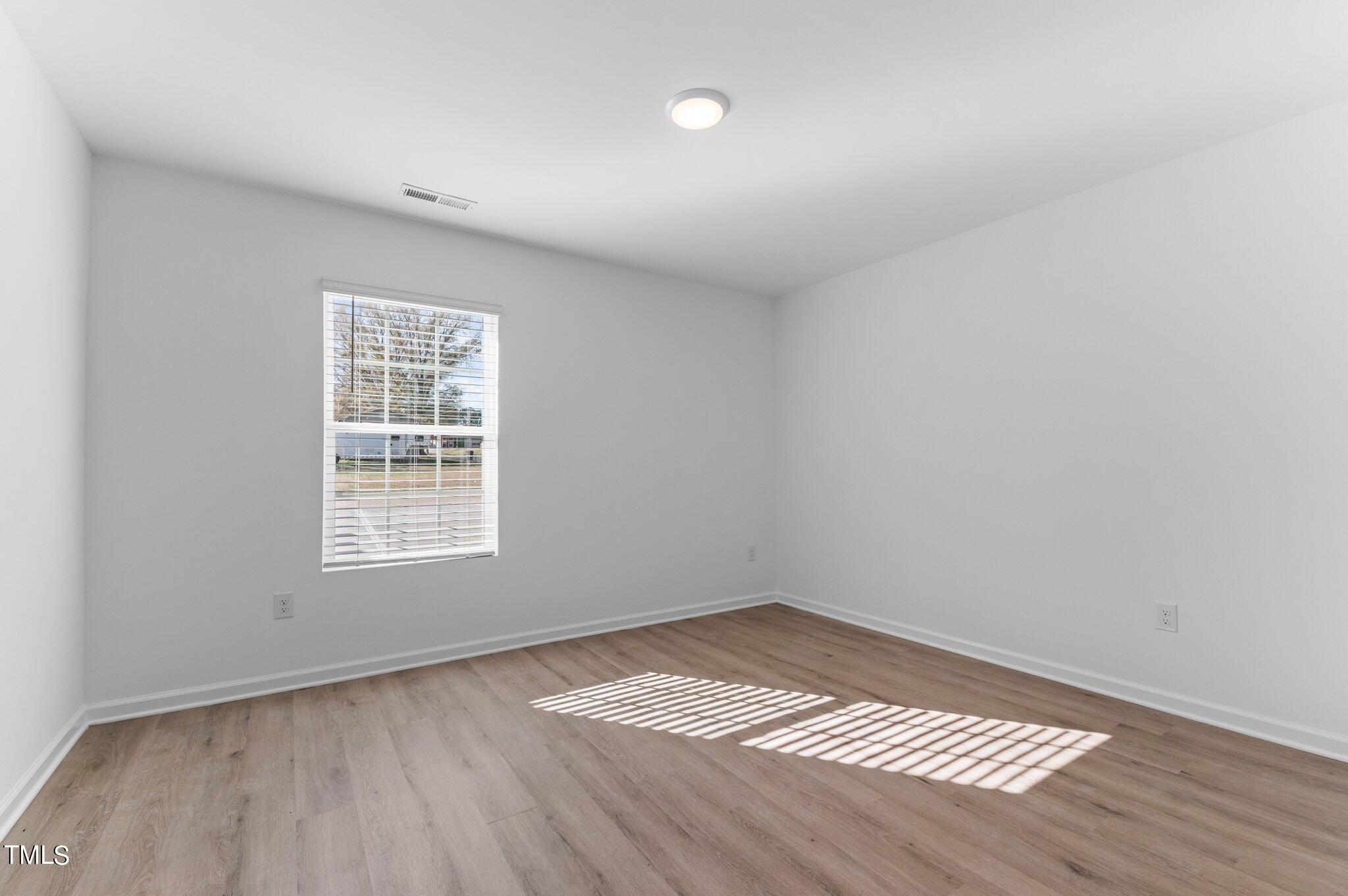 207 South Nash Street, Unit AB Bunn, NC 27508 - Photo 8 of 25 an empty room with wooden floor and windows