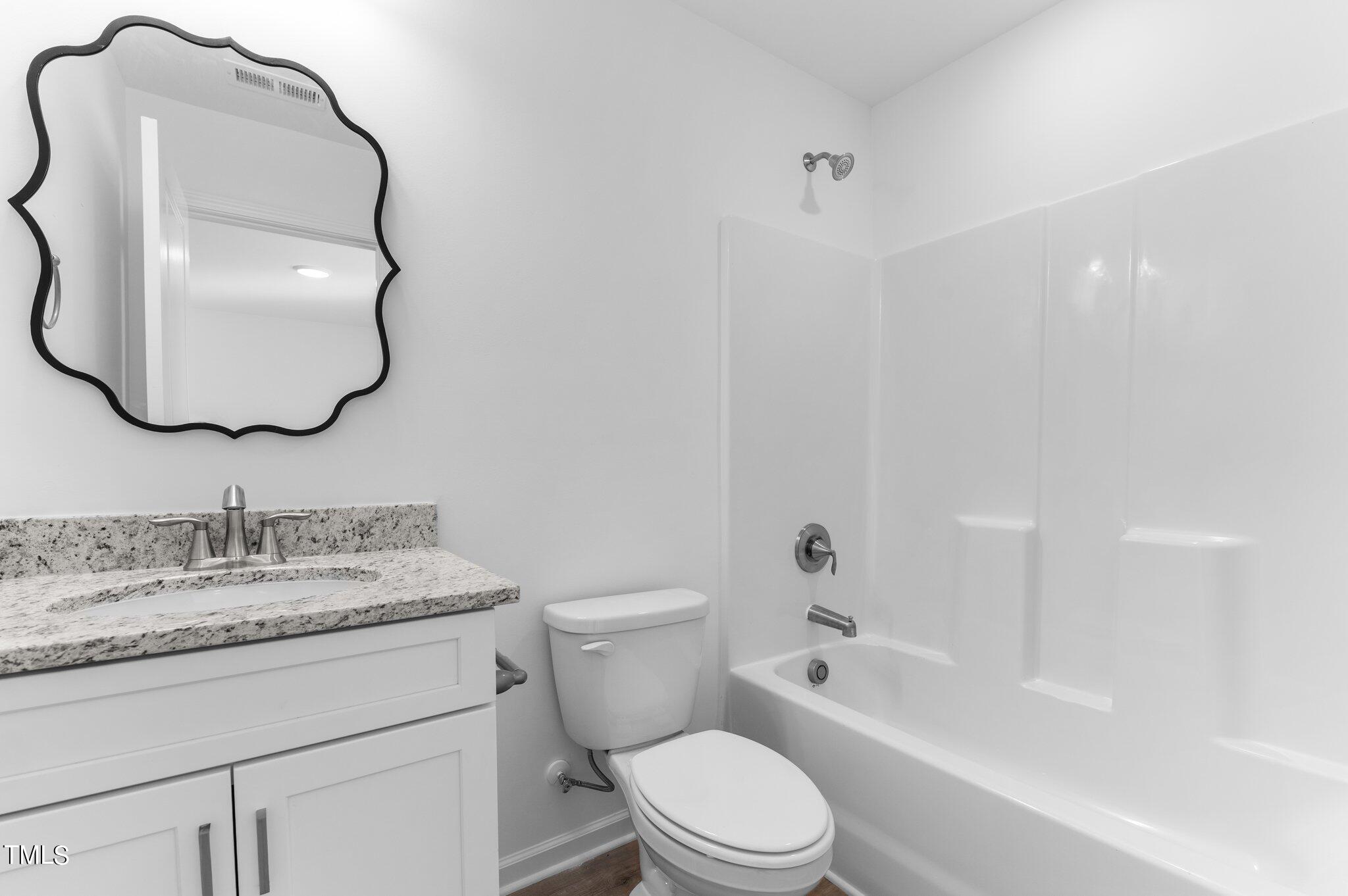 207 South Nash Street, Unit AB Bunn, NC 27508 - Photo 10 of 25 a bathroom with a toilet sink vanity tub and mirror
