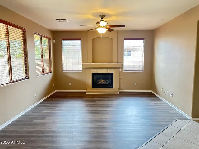 an empty room with wooden floor fireplace and windows