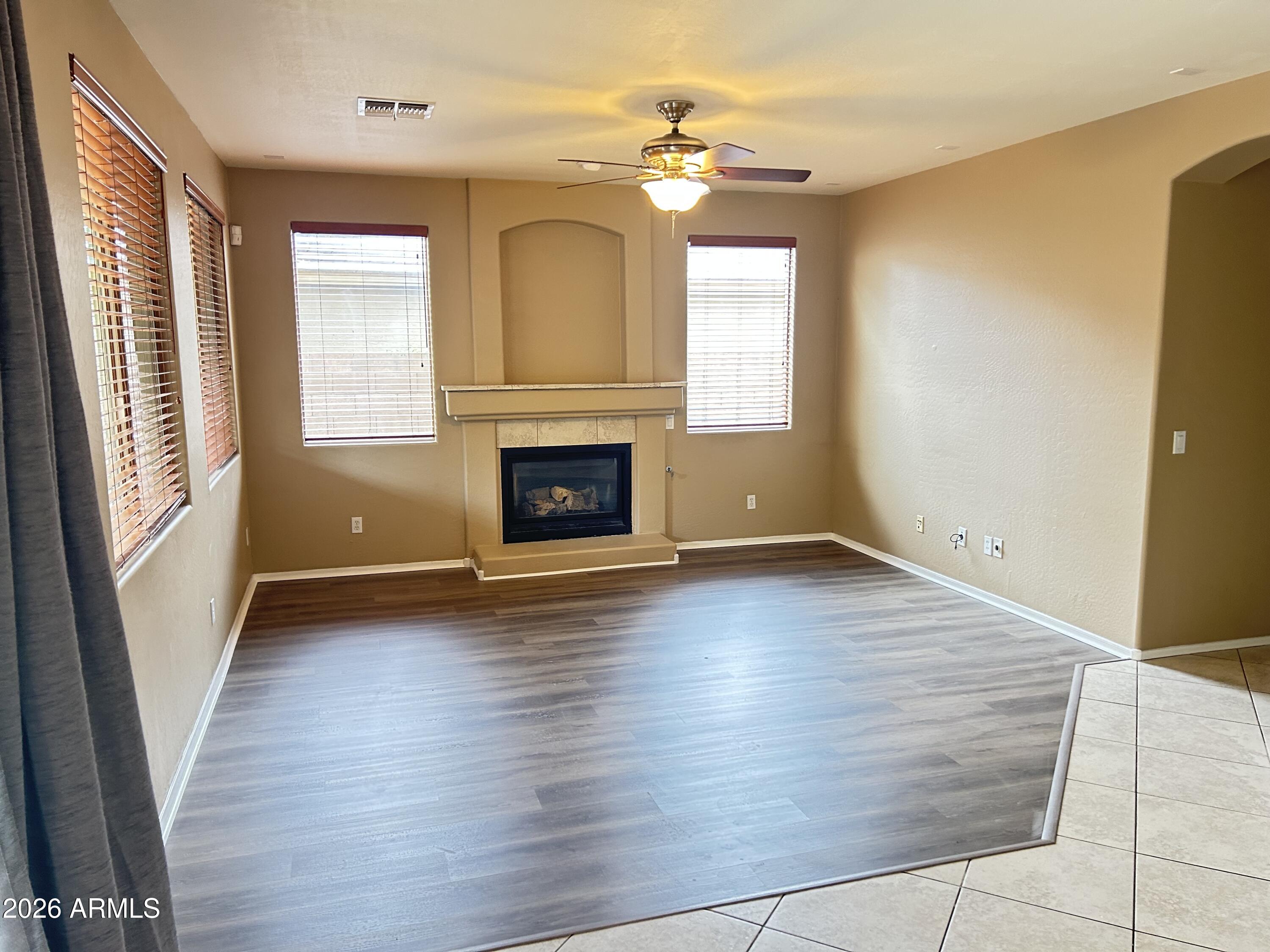 7089 West Eagle Ridge Lane Peoria, AZ 85383 - Photo 8 of 27 an empty room with wooden floor fireplace and windows