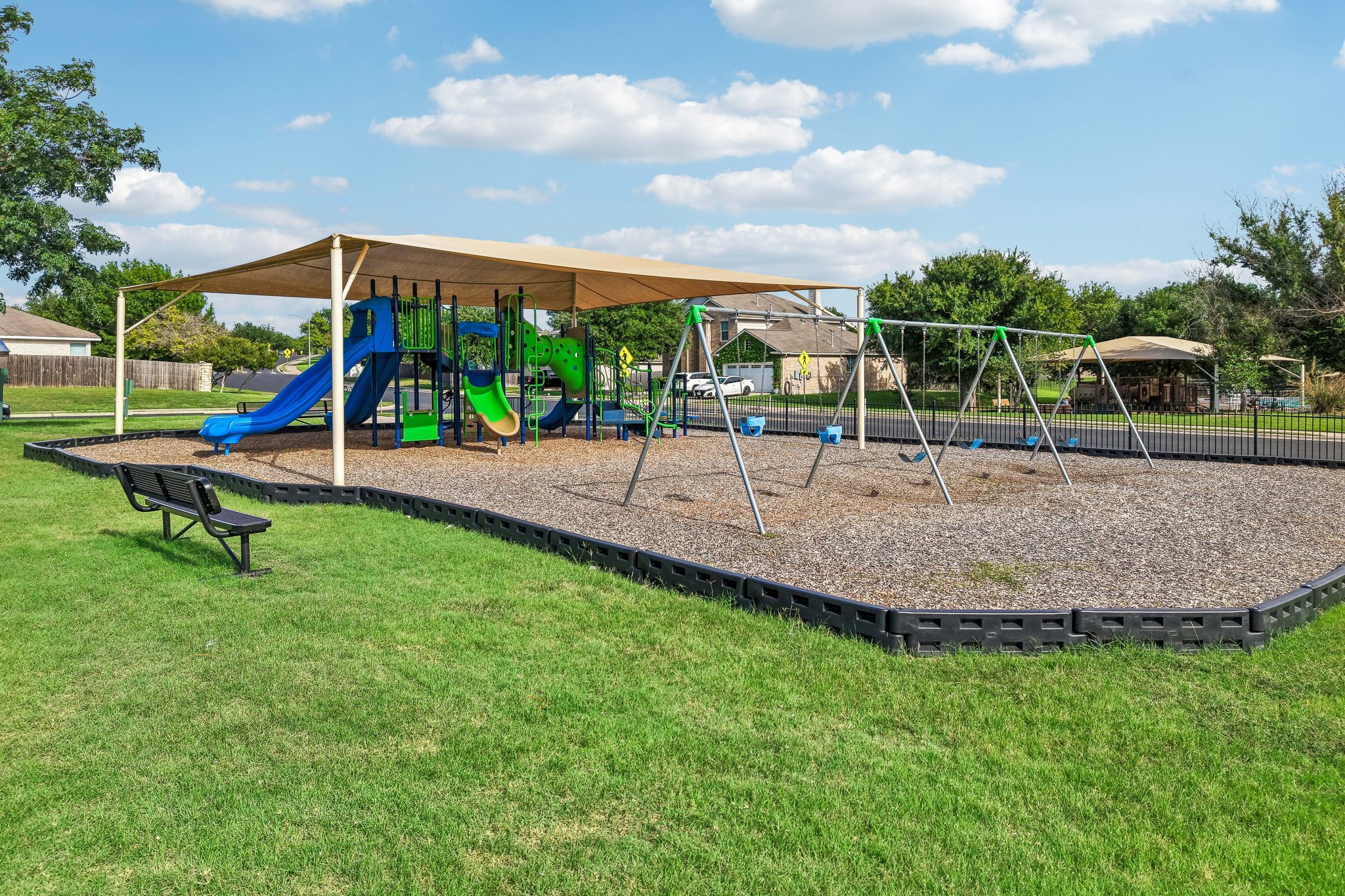 1721 Long Rifle Drive Austin, TX 78754 - Photo 33 of 38 A vibrant playground with swings and slides invites family fun under a protective shade structure.