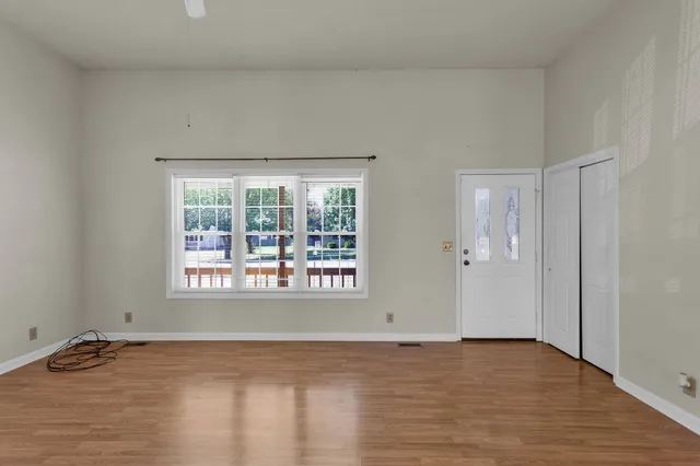 a view of an empty room with wooden floor and a window