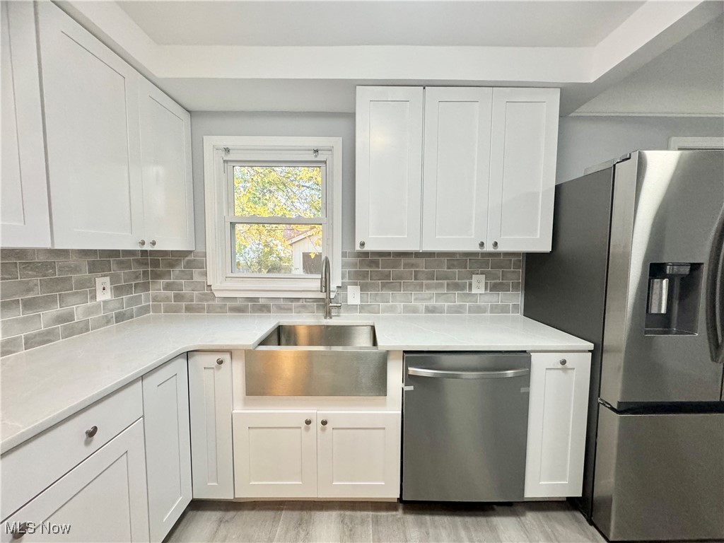 1215 Avondale Road Cleveland, OH 44121 - Photo 3 of 27 Kitchen with white cabinetry, light hardwood / wood-style floors, tasteful backsplash, and appliances with stainless steel finishes