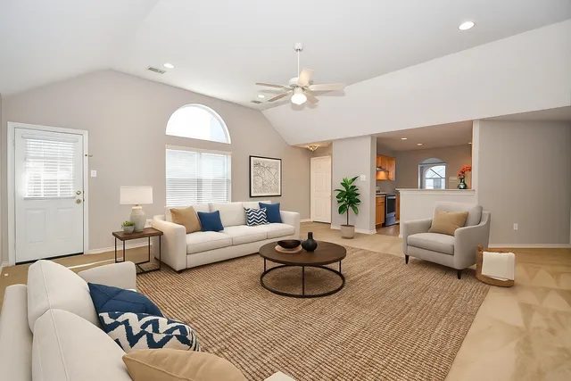 a living room with furniture ceiling fan and a large window
