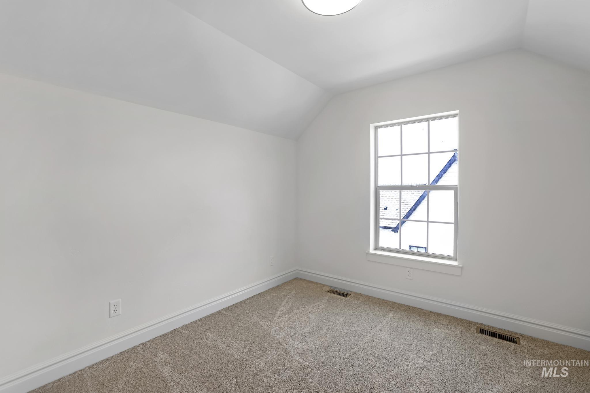 866 Quartz Road Kimberly, ID 83341 - Photo 44 of 48 Room featuring sloped ceilings, white painted walls, a double-hung window with grid inserts, light-colored carpet flooring, and baseboard trim
