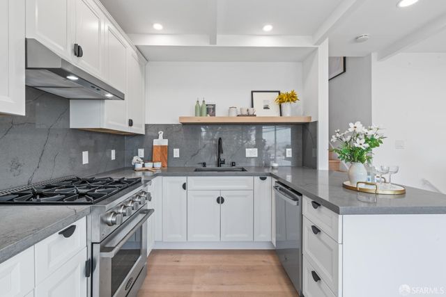 a kitchen with stainless steel appliances granite countertop a sink a stove and cabinets