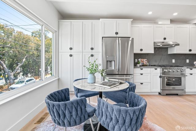 a kitchen with stainless steel appliances granite countertop a refrigerator a sink a stove and chairs