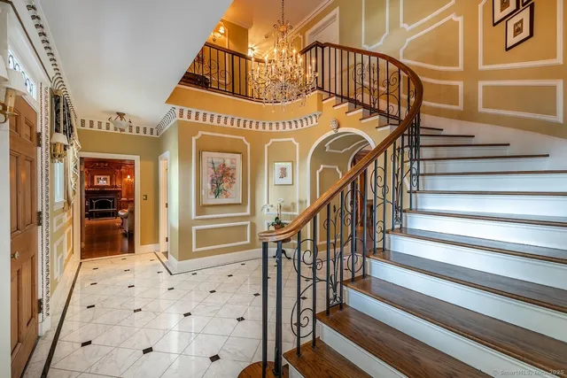 a view of a staircase with white walls and a chandelier