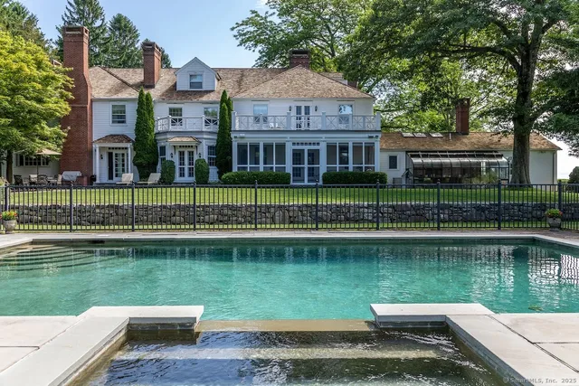 a view of a house next to a lake with a large trees