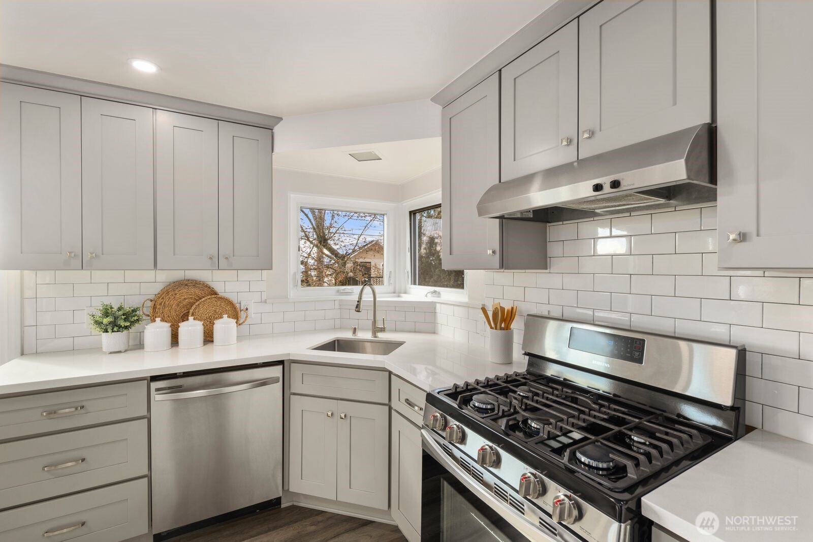 6023 35th Avenue Southwest Seattle, WA 98126 - Photo 13 of 38 a kitchen with white cabinets a sink stove and wooden floors