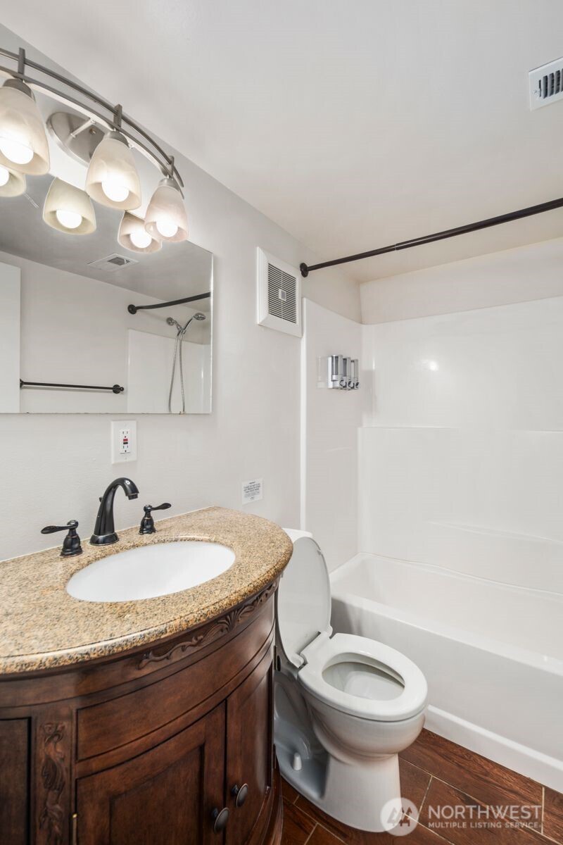 6023 35th Avenue Southwest Seattle, WA 98126 - Photo 26 of 38 a bathroom with a granite countertop sink toilet a mirror a vanity and shower