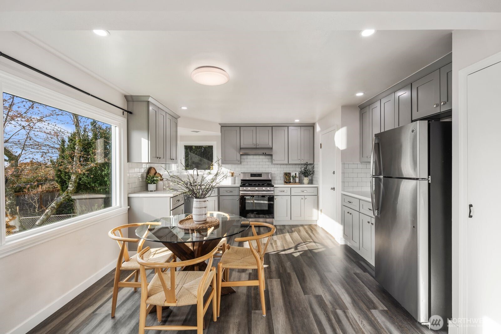 6023 35th Avenue Southwest Seattle, WA 98126 - Photo 9 of 38 a kitchen with a refrigerator a stove top oven and a dining table with wooden floor