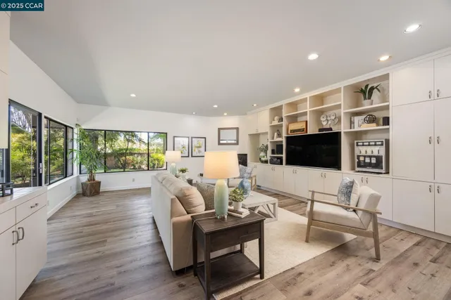 a living room with furniture a flat screen tv and a floor to ceiling window