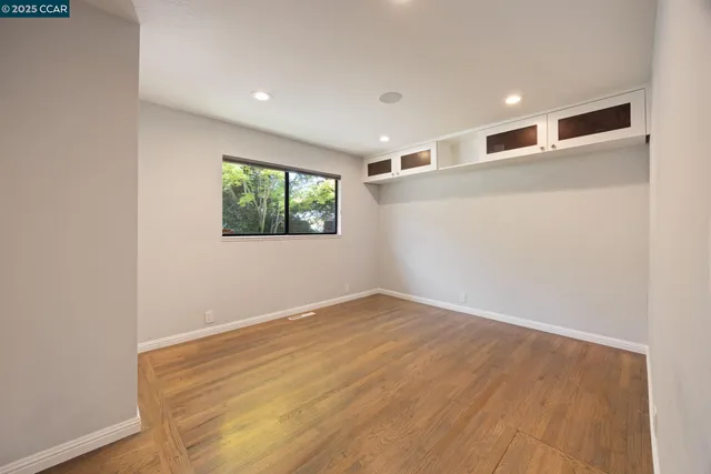 an empty room with wooden floor and windows