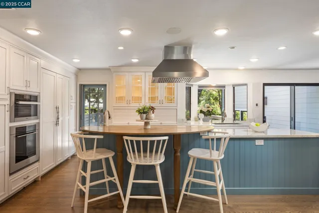 a kitchen with stainless steel appliances a dining table chairs and wooden floor
