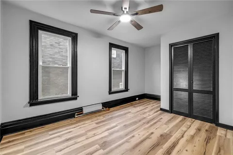 a view of empty room with wooden floor and fan