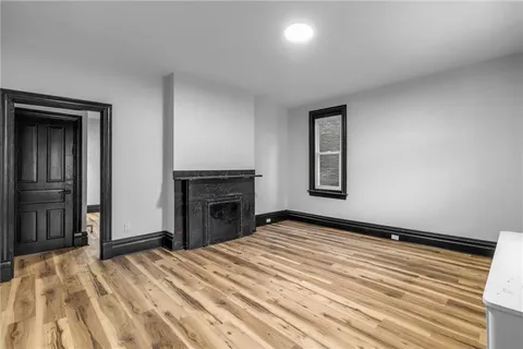 a view of empty room with a fireplace and wooden floor