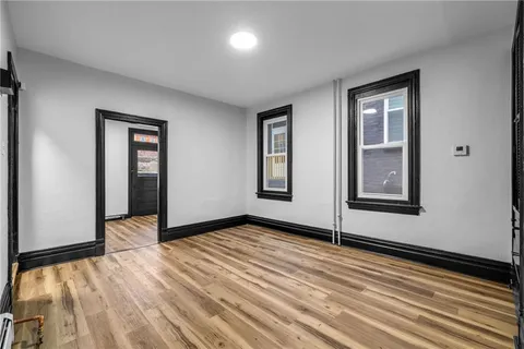 a view of an empty room with wooden floor and closet