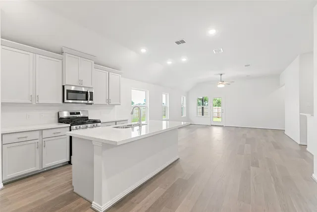 a kitchen with granite countertop a stove top oven a sink dishwasher and a refrigerator with wooden floor