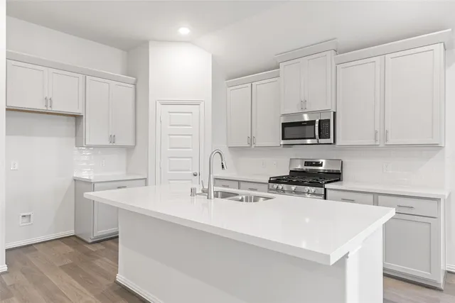 a kitchen with stainless steel appliances a sink a stove a microwave and cabinets