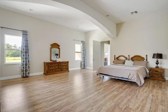 a spacious bedroom with a bed and wooden floor