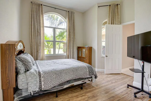 a bedroom with a bed tv and wooden floor