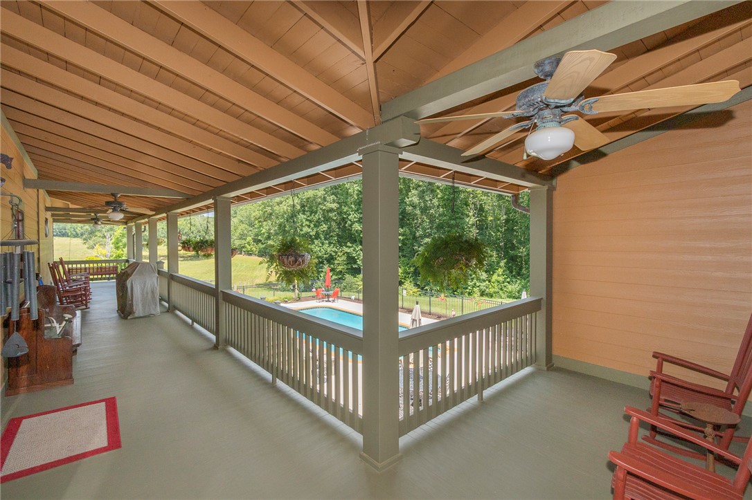 911 State Rd S-4-203 Belton, SC 29627 - Photo 37 of 49 A spacious covered porch offers scenic views of the lush landscape and private pool, perfect for outdoor relaxation.