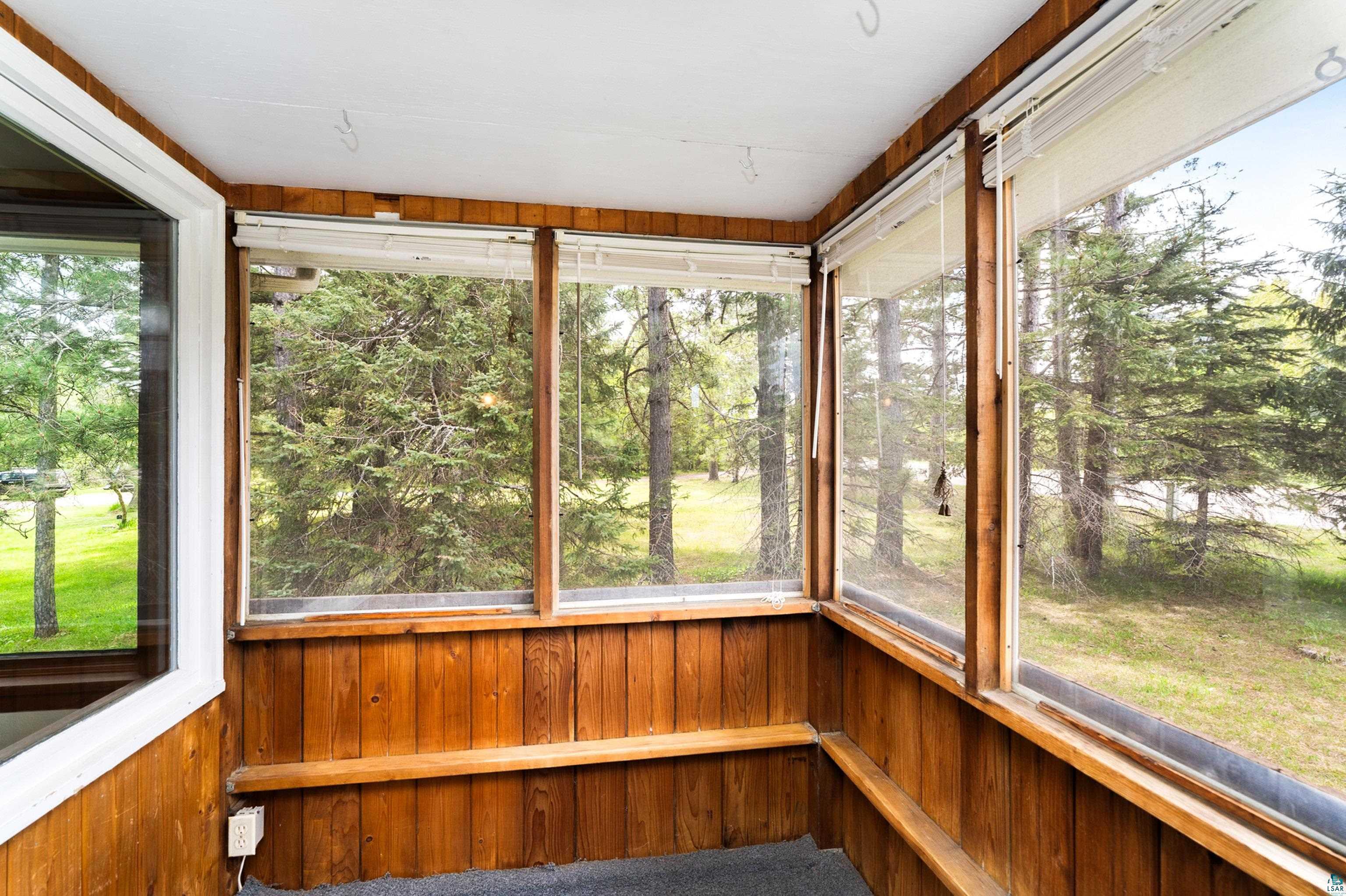 4808 Midway Road Duluth, MN 55811 - Photo 14 of 57 Screened-in porch featuring wood paneling, multiple large windows, and built-in wood benches