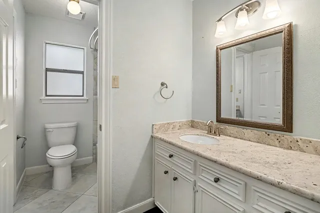 a bathroom with a granite countertop sink a toilet and a mirror
