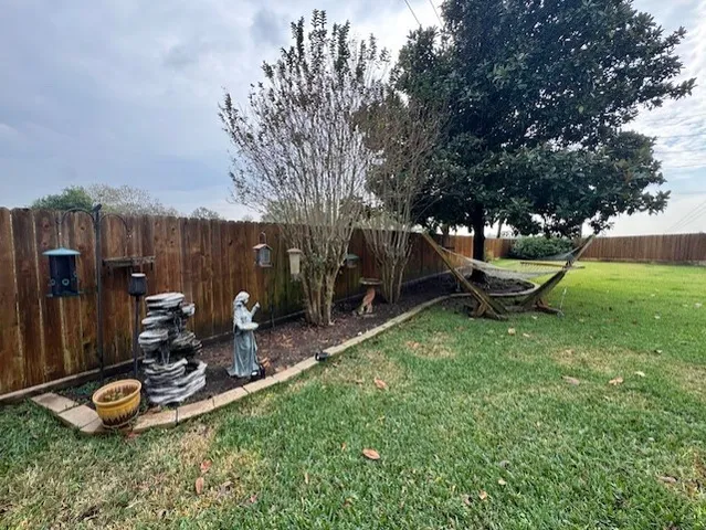 a view of a backyard with plants and wooden fence