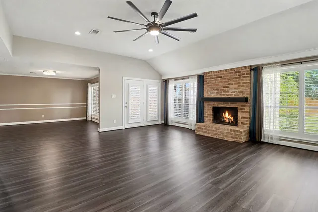 an empty room with wooden floor a fireplace and a ceiling fan