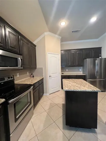 a kitchen with stainless steel appliances granite countertop a stove a microwave and a refrigerator