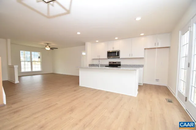 a large kitchen with stainless steel appliances kitchen island a large counter top and a wooden floors