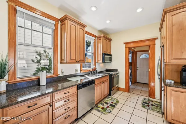 a large kitchen with granite countertop a stove a sink and a refrigerator