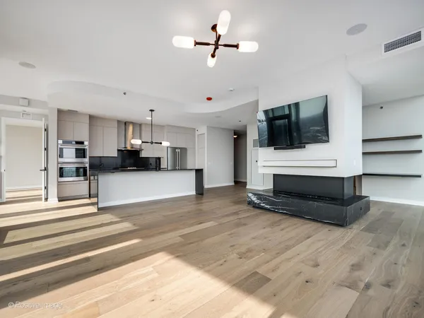 a view of living room kitchen with stainless steel appliances cabinets and flat screen tv