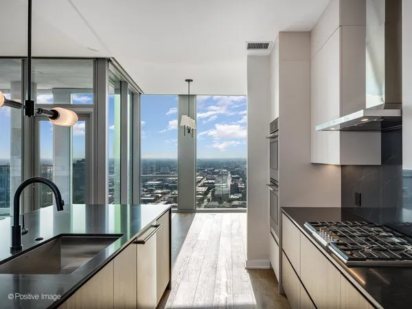 a large kitchen with kitchen island a large counter top appliances a chandelier and living room view