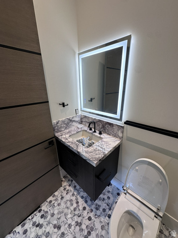 1918 Chimney Rock Road Heber City, UT 84032 - Photo 43 of 74 Bathroom vanity featuring a floating dark wood-finish cabinet with black hardware, a stone countertop, an under-mount sink with a matte black faucet, and an illuminated mirror