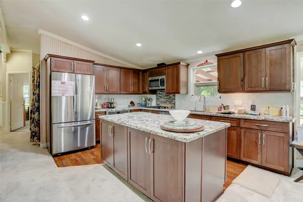 a kitchen with stainless steel appliances granite countertop a refrigerator a sink a stove a microwave and island